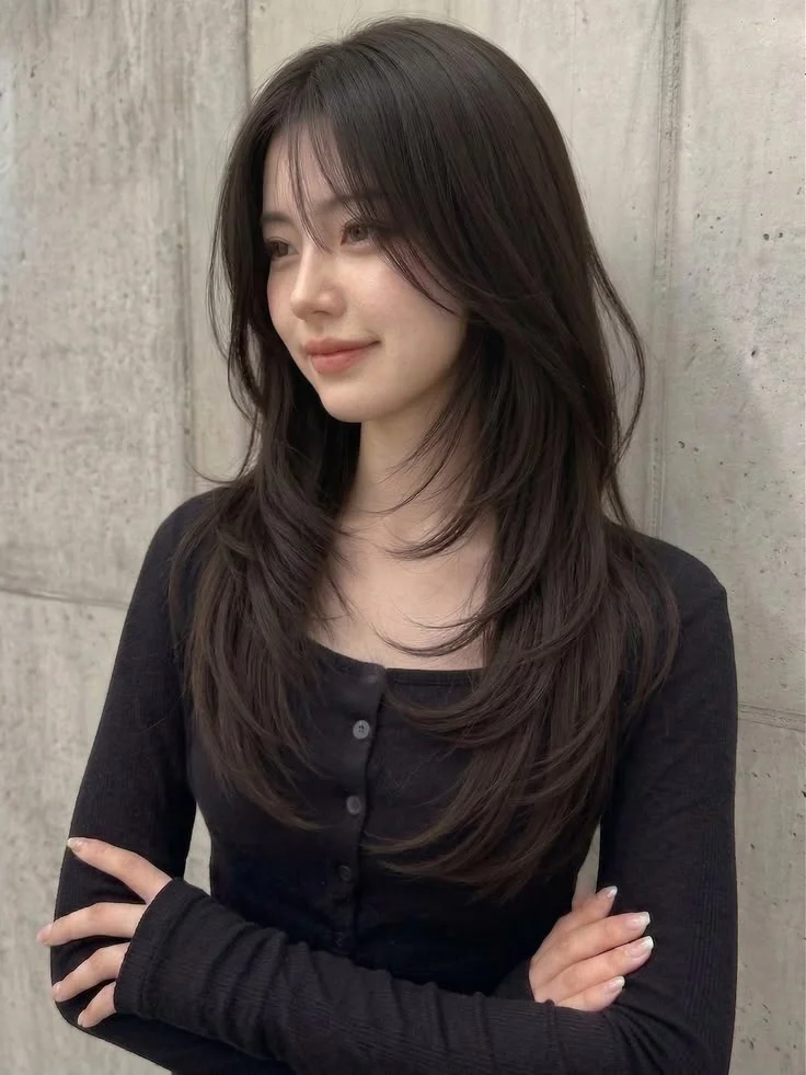 Long dark hair with face-framing layers and wispy bangs